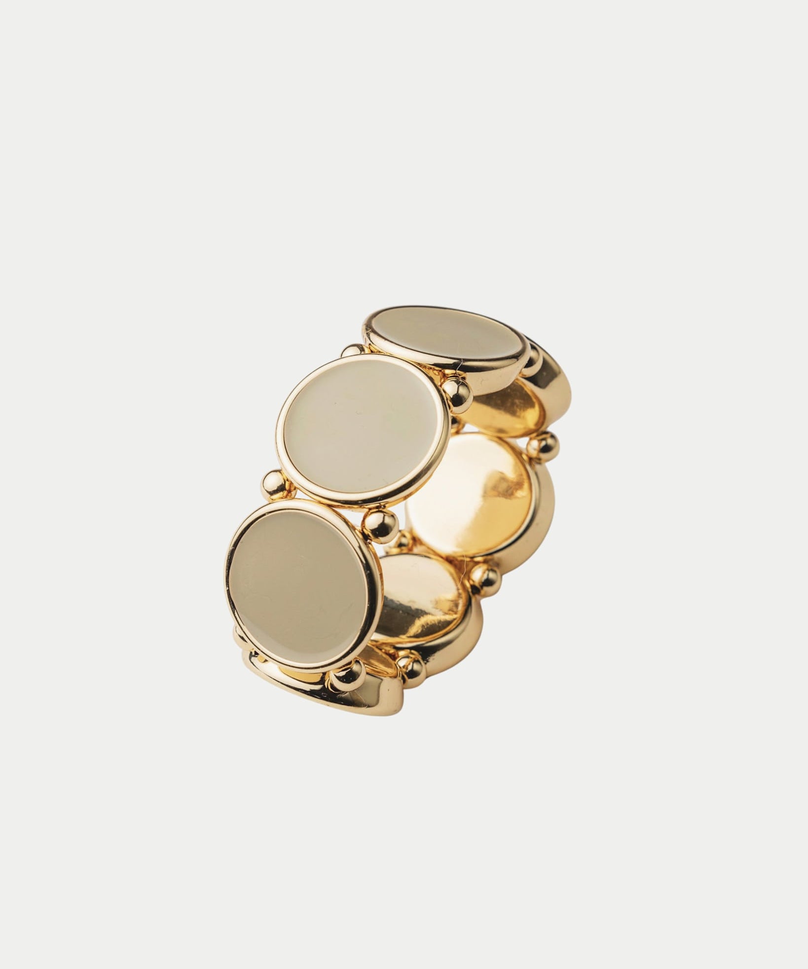 Elastiskt armband med runda plattor som har en guldkant i beige