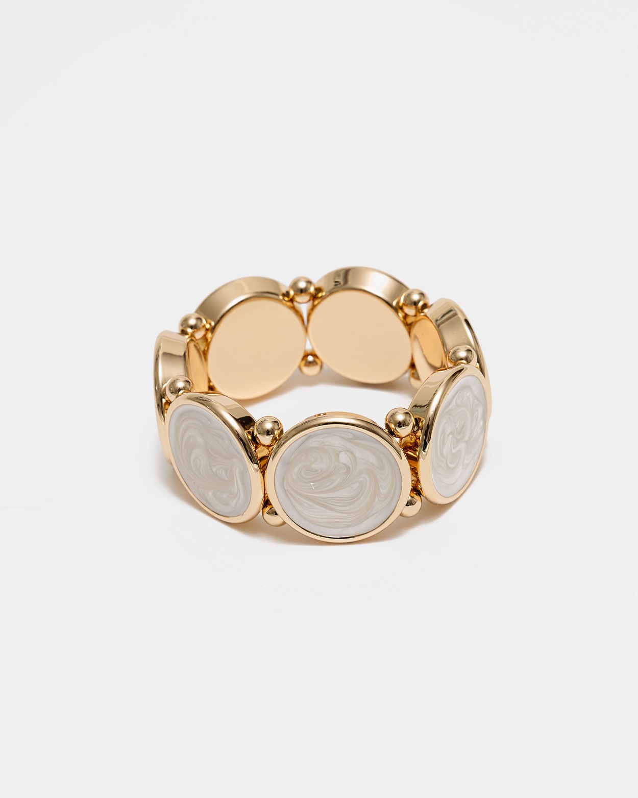 Elastiskt armband med runda plattor som har en guldkant i pärlvit