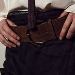 Person wearing a white shirt and dark pants with a brown belt.