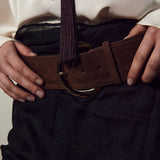 Person wearing a white shirt and dark pants with a brown belt.